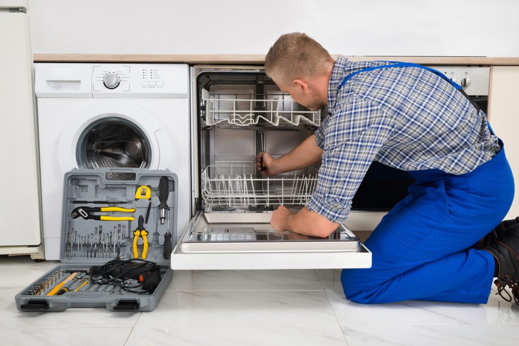 Man In Overall With Toolbox Repairing Dishwasher